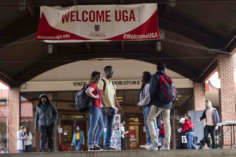 Students talking underneath a Welcome UGA banner at the Tate Quad